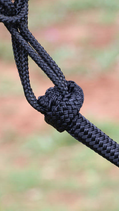 Close-up of a knotted black rope against a blurred natural background
